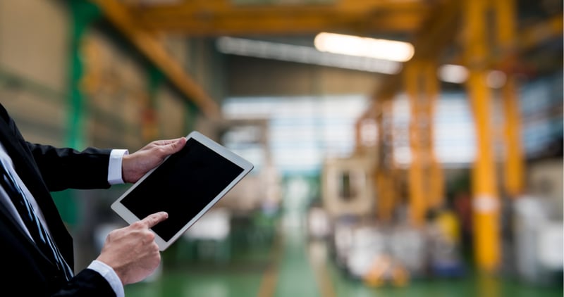 businessman using ipad to track at a factory