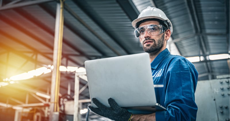 Factory worker focused while holding laptop at a factory