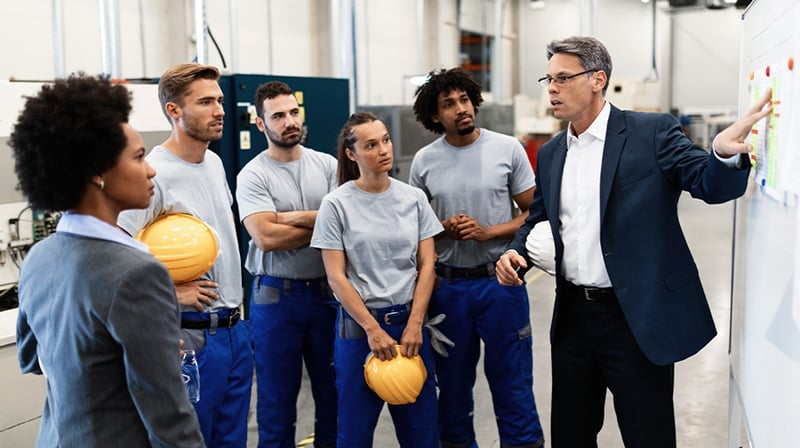 manufacturing consultant speaking to a group of factory workers